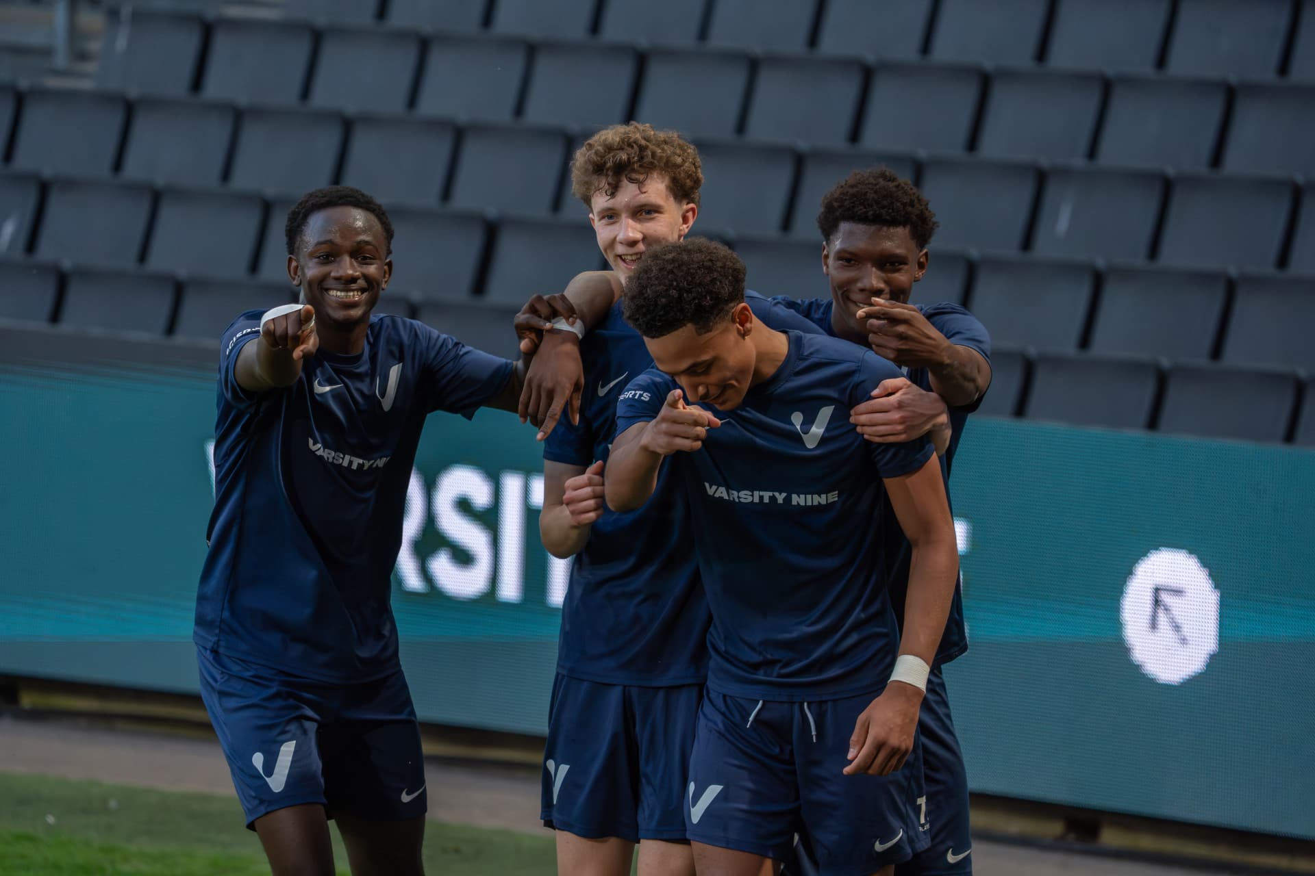 Four teammates celebrating together in front of the stands