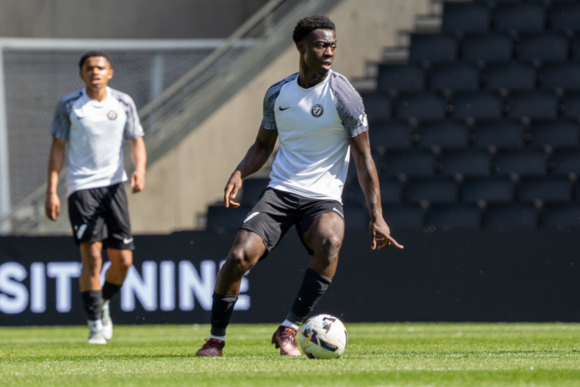 Midfielder in a white Varsity Nine kit controlling possession
